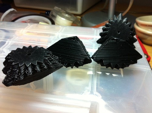 A collection of 4 3D printed eccentric gears in black ABS plastic. Layer lines are quite visible.