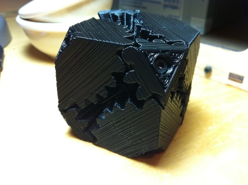A cube made up of a mechanism of black 3D printed gears.